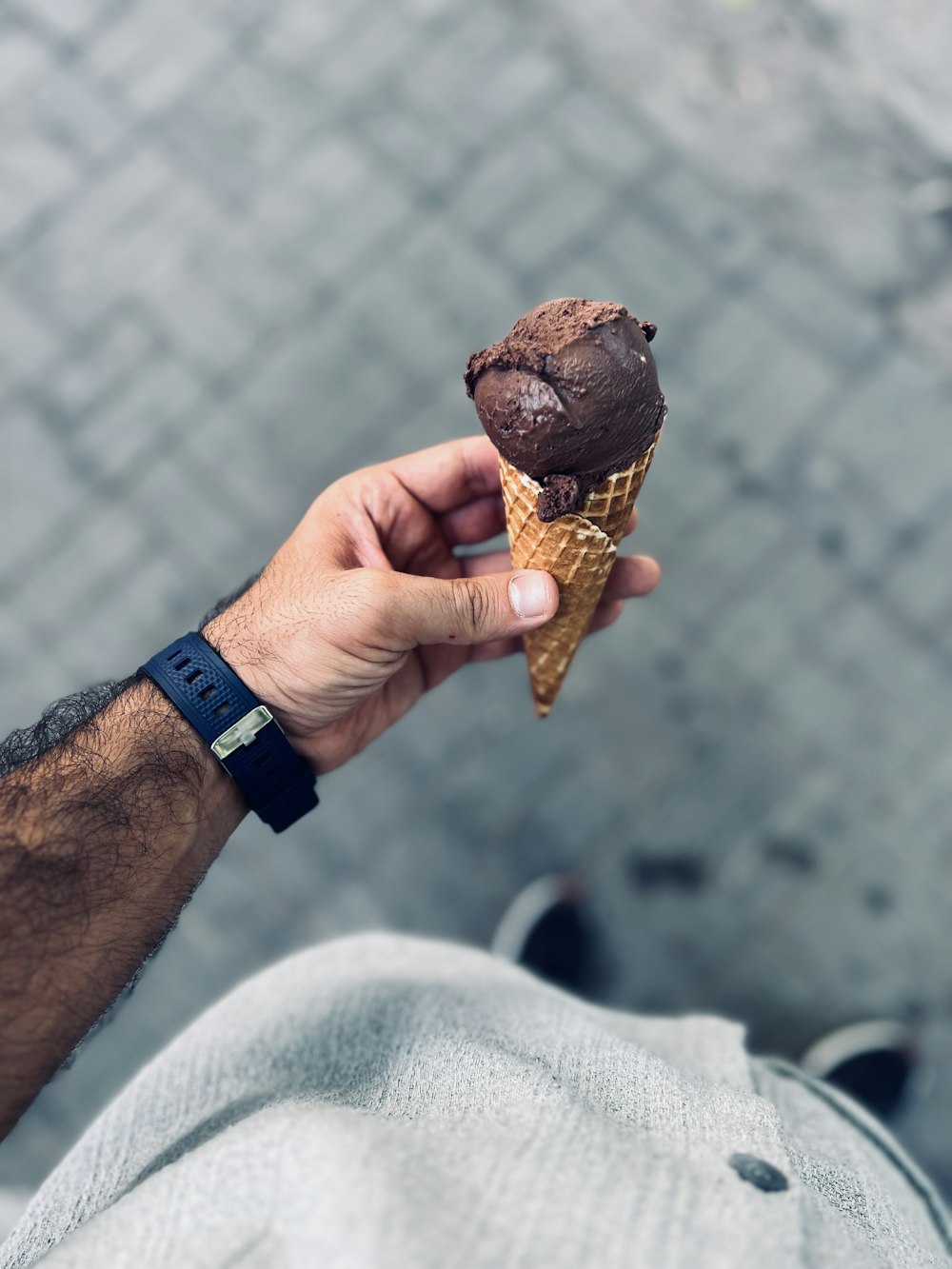 a hand holding a chocolate ice cream cone