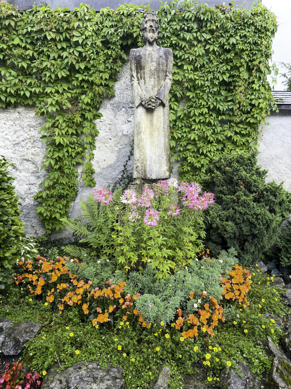 a garden with a statue surrounded by flowers