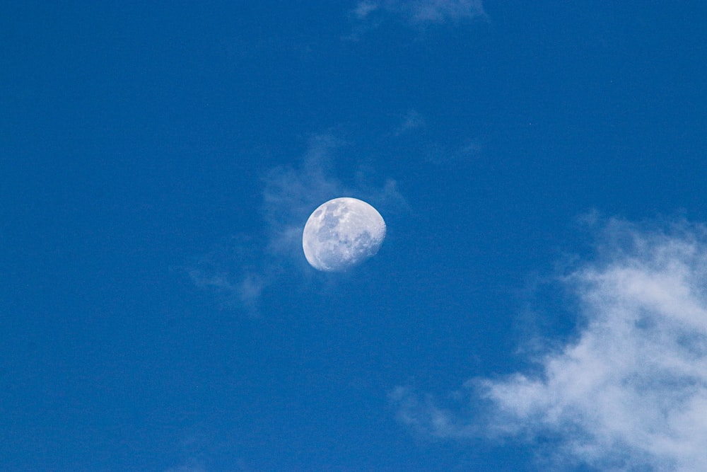 a full moon in a blue sky with clouds