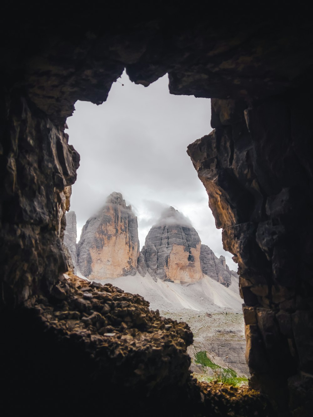 une vue des montagnes à travers un trou dans une formation rocheuse