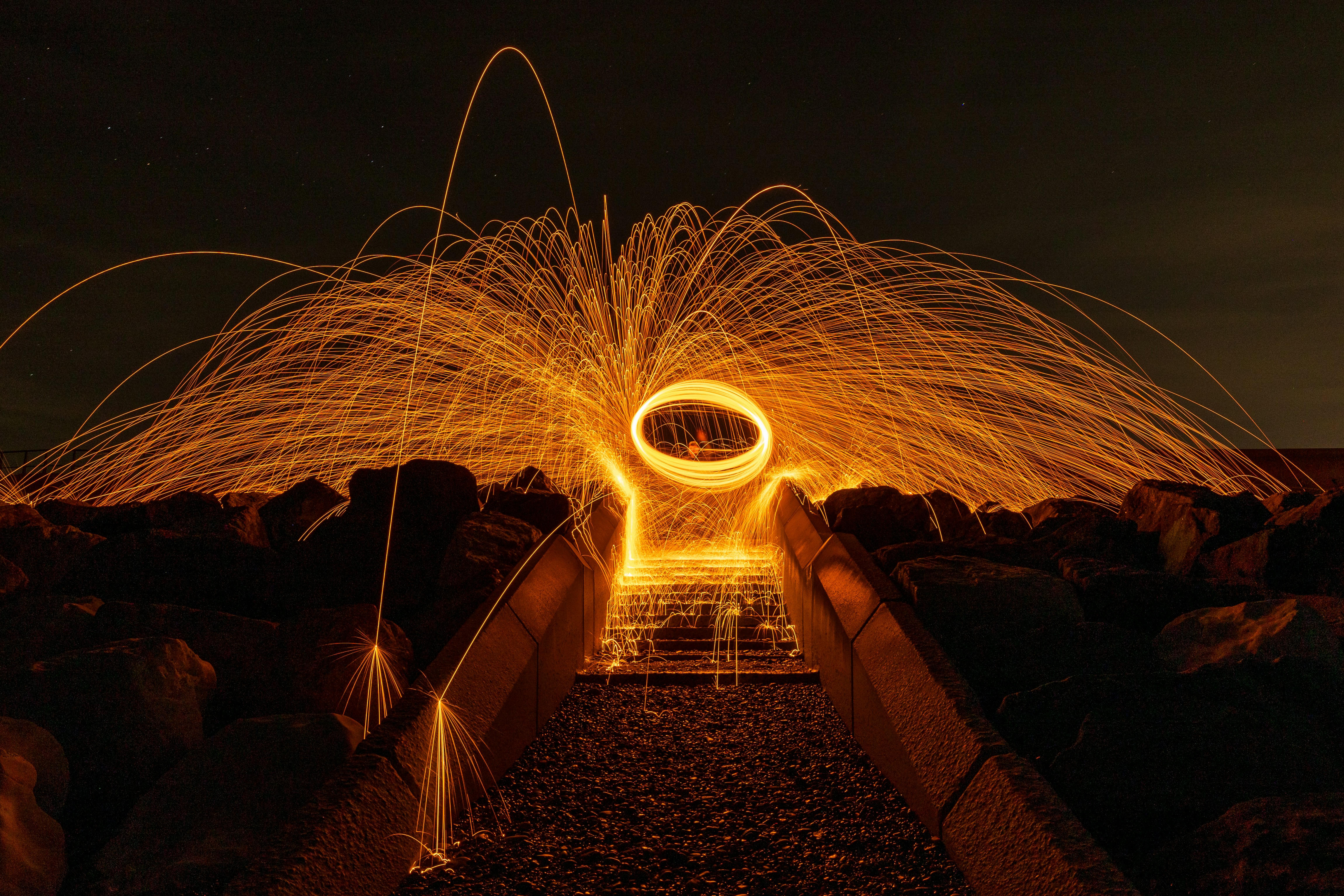 a steel wool spinning on a bridge at night