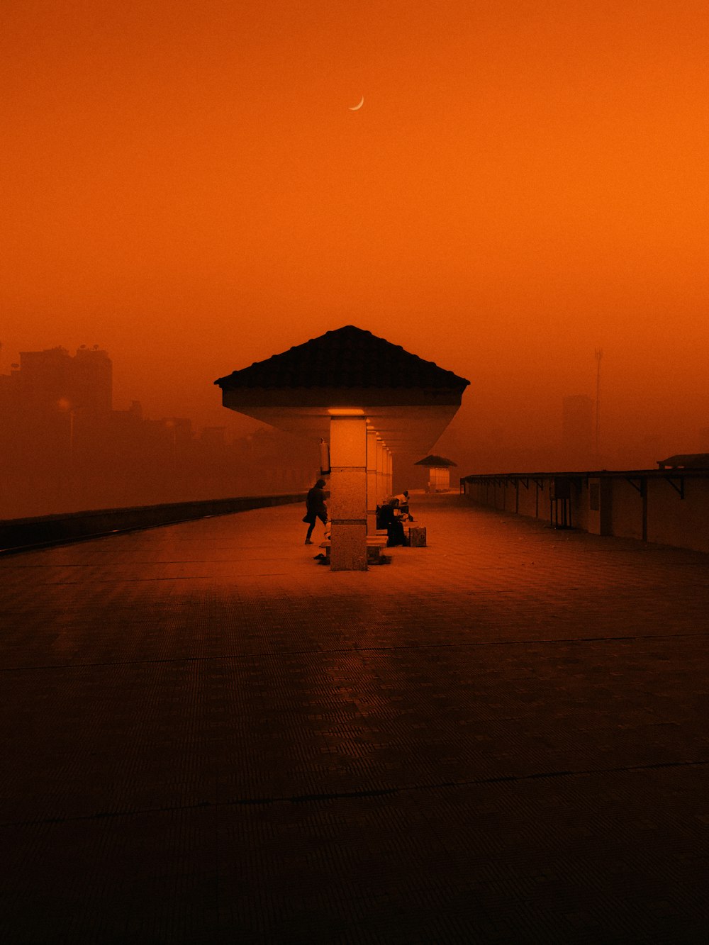 a person sitting on a bench under an umbrella