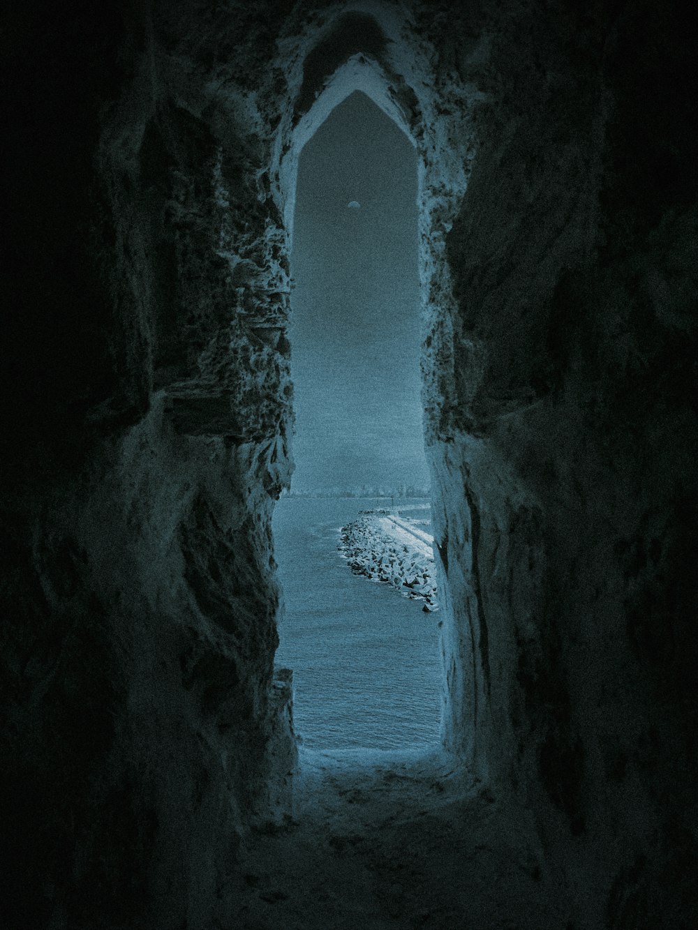 a dark tunnel leading to a body of water