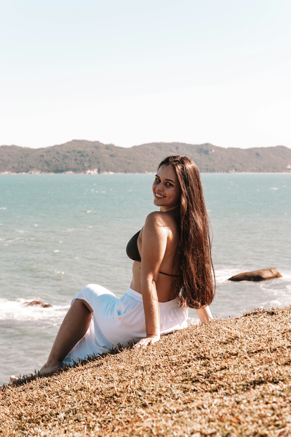 a woman sitting on a beach next to the ocean