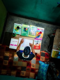A focused student studying with books and notes spread out on a desk.