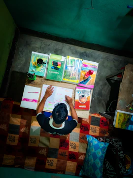 A focused student with books and a laptop, surrounded by international university brochures.