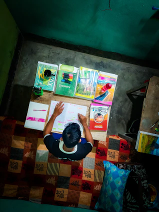 A student happily studying at a desk with colorful educational materials around.