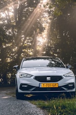 A modern car parked on a scenic road surrounded by lush greenery.