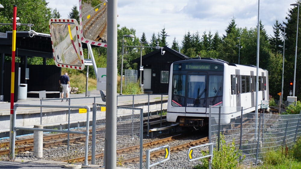 a white train traveling down train tracks next to a forest