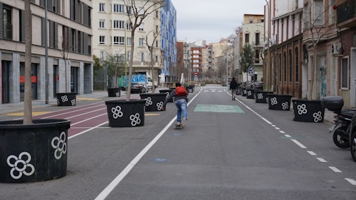 Skateboard wheels rolling over cracked pavement with city buildings behind.