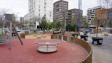 Children playing in a newly built urban park surrounded by modern buildings.