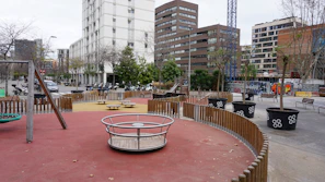 Children playing in a newly built urban park surrounded by modern buildings.