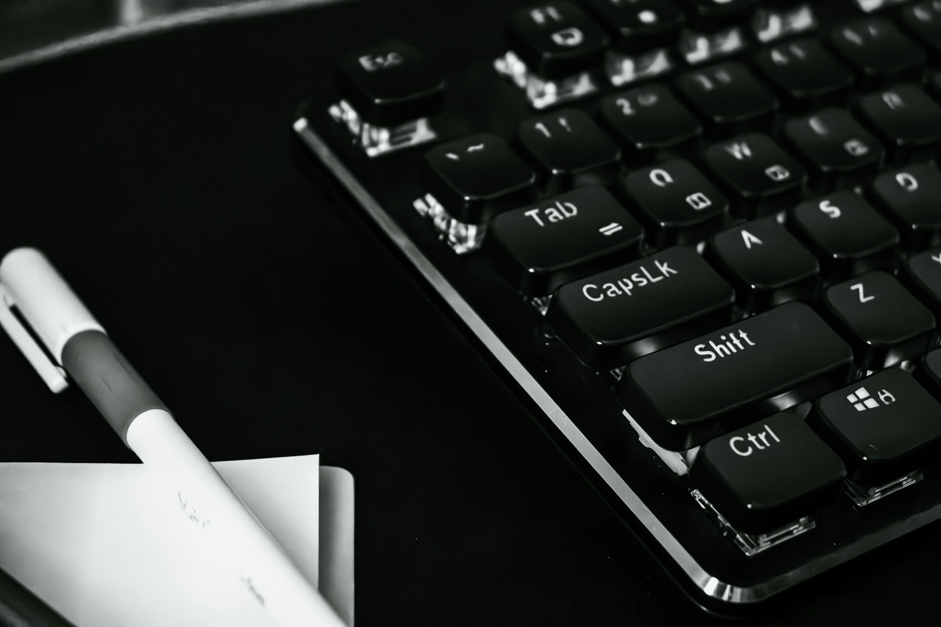 a black and white photo of a keyboard and a pen
