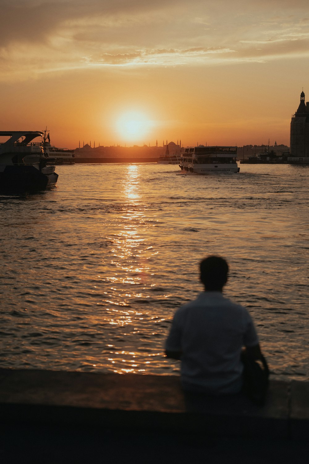 a man sitting on a ledge watching the sun set