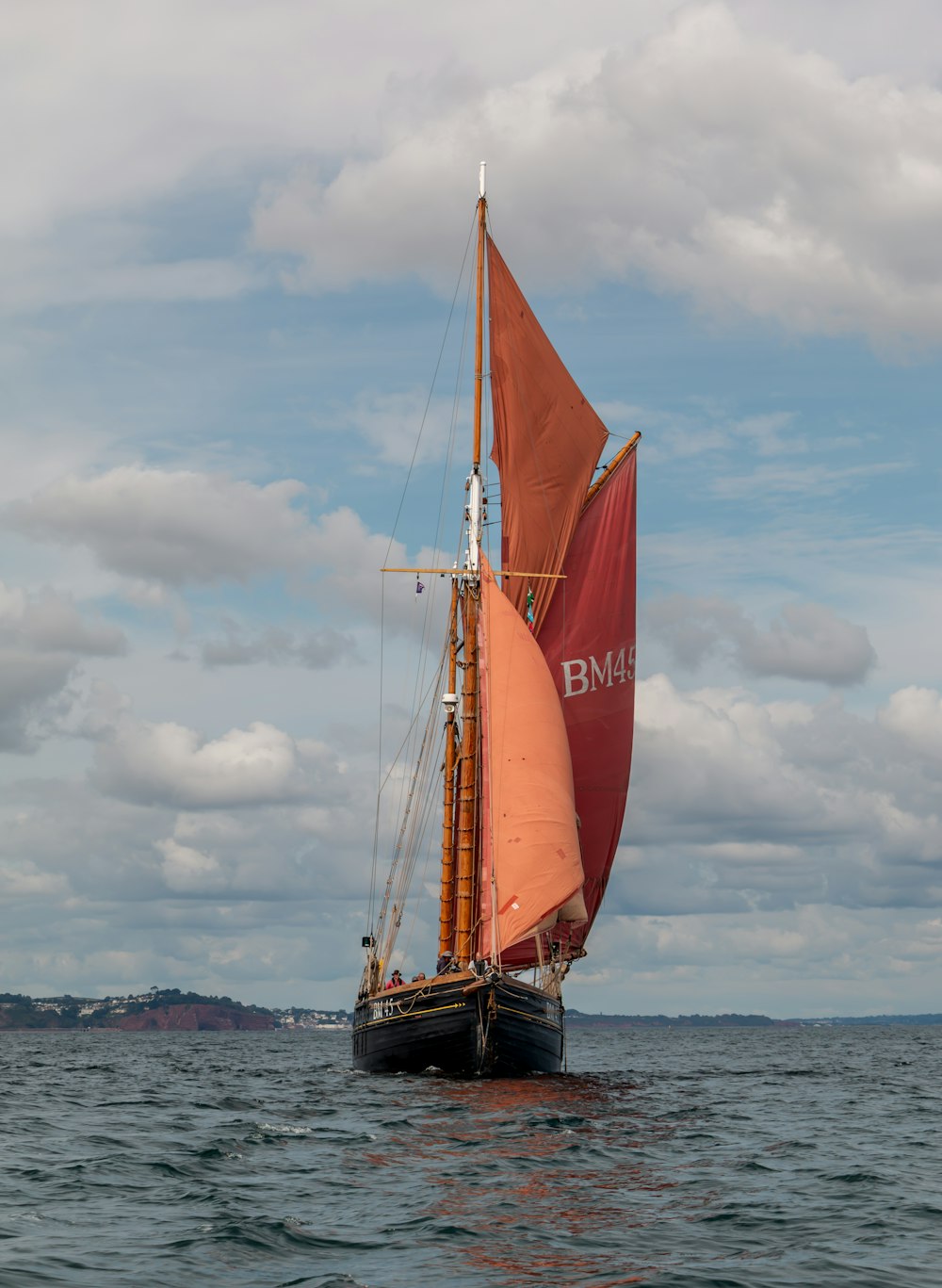 a sailboat with a red sail on a body of water