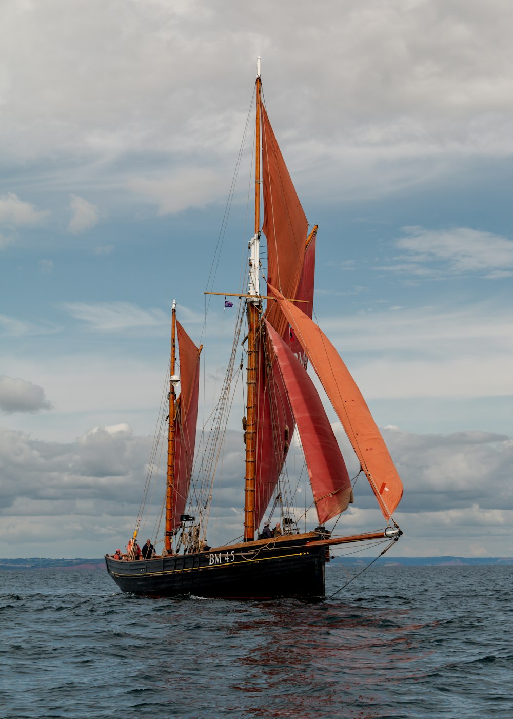 a sailboat with orange sails in the ocean