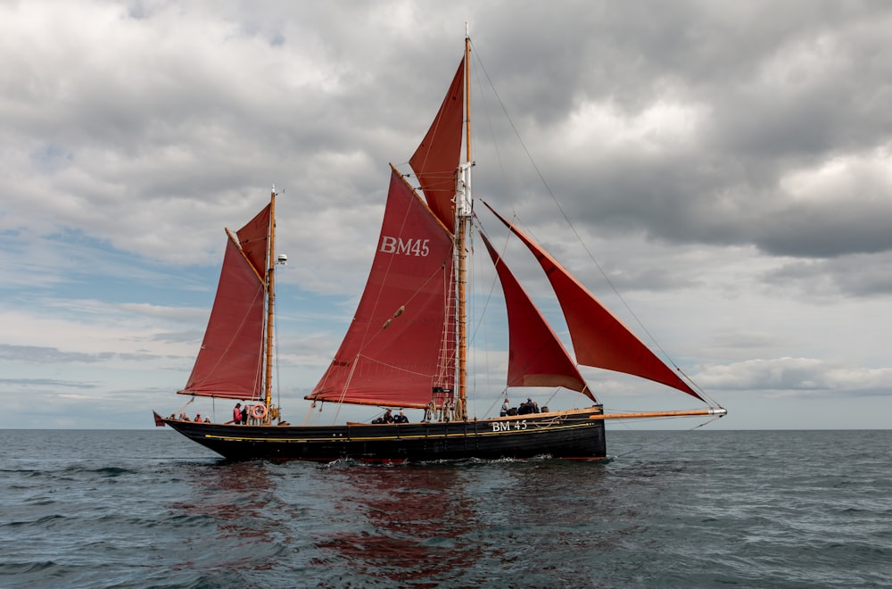 a sailboat with red sails on the water