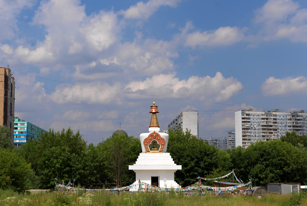 a large white and gold clock tower in a field