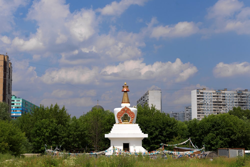 Una gran torre de reloj blanca y dorada en un campo