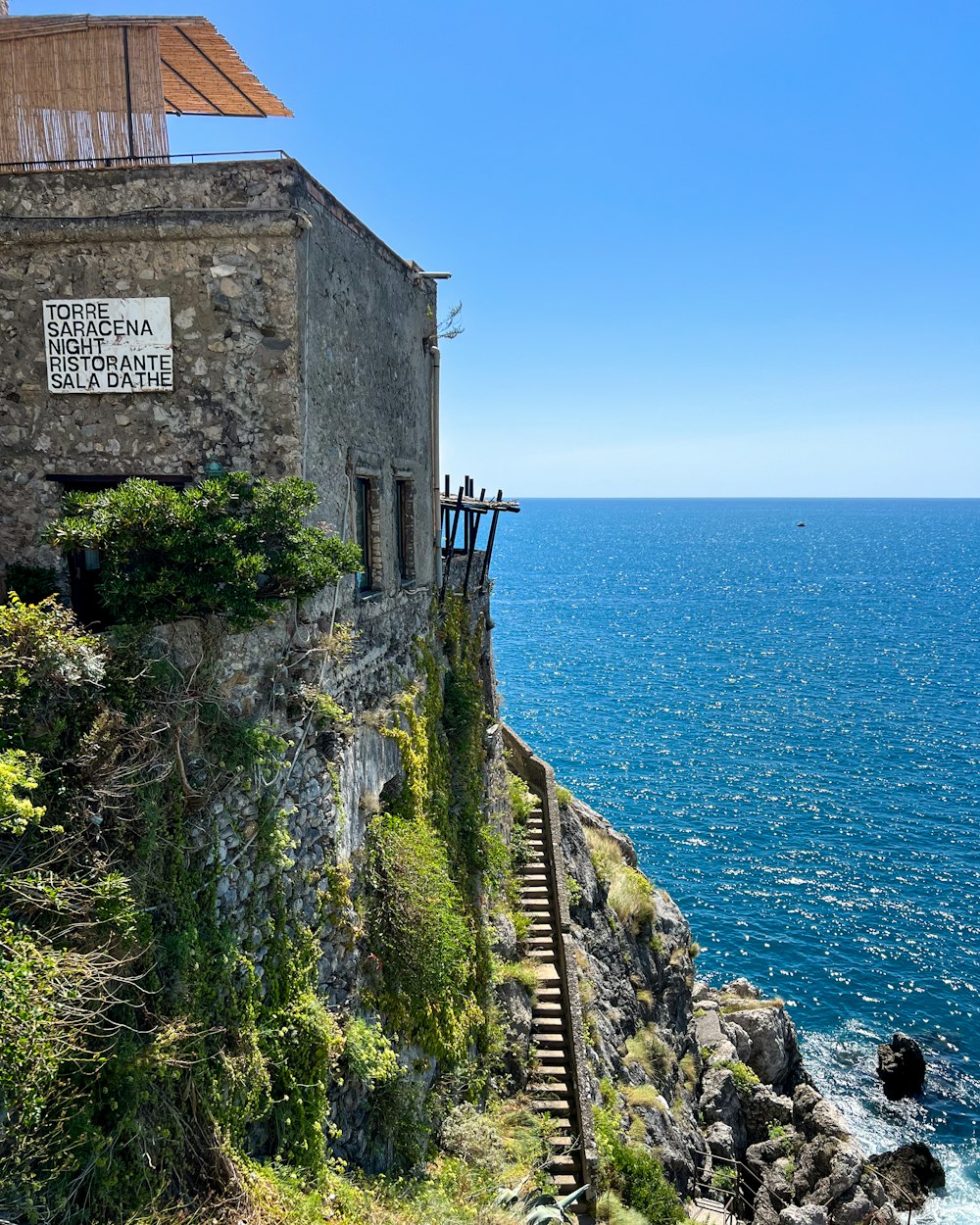 a stone building sitting on top of a cliff next to the ocean