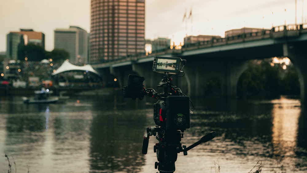 a camera set up on a tripod in front of a body of water