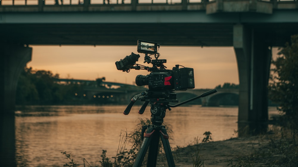 a camera set up on a tripod with a bridge in the background