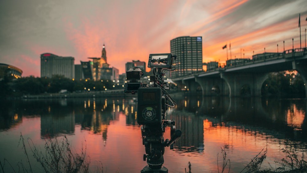 a camera sitting on top of a tripod next to a body of water