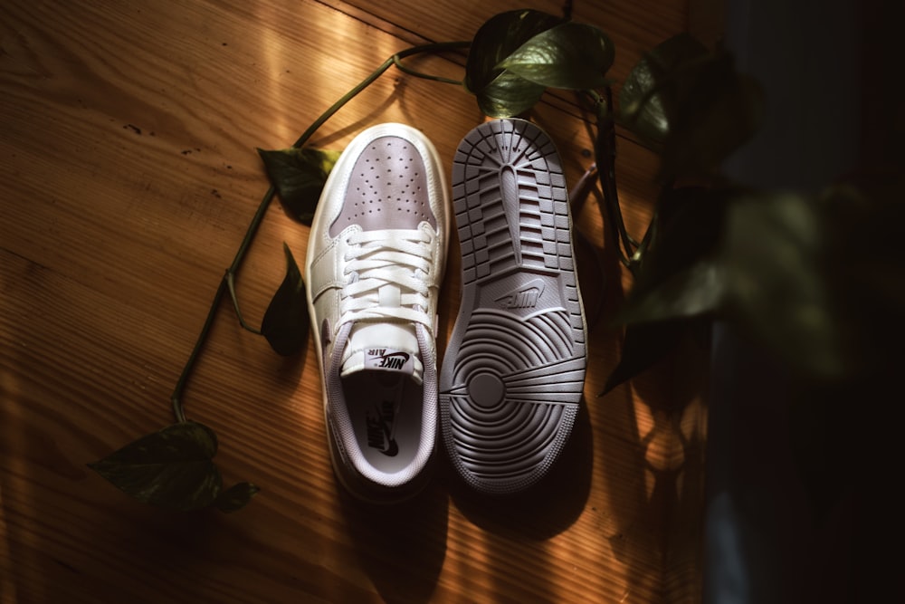 a pair of white sneakers sitting on top of a wooden floor