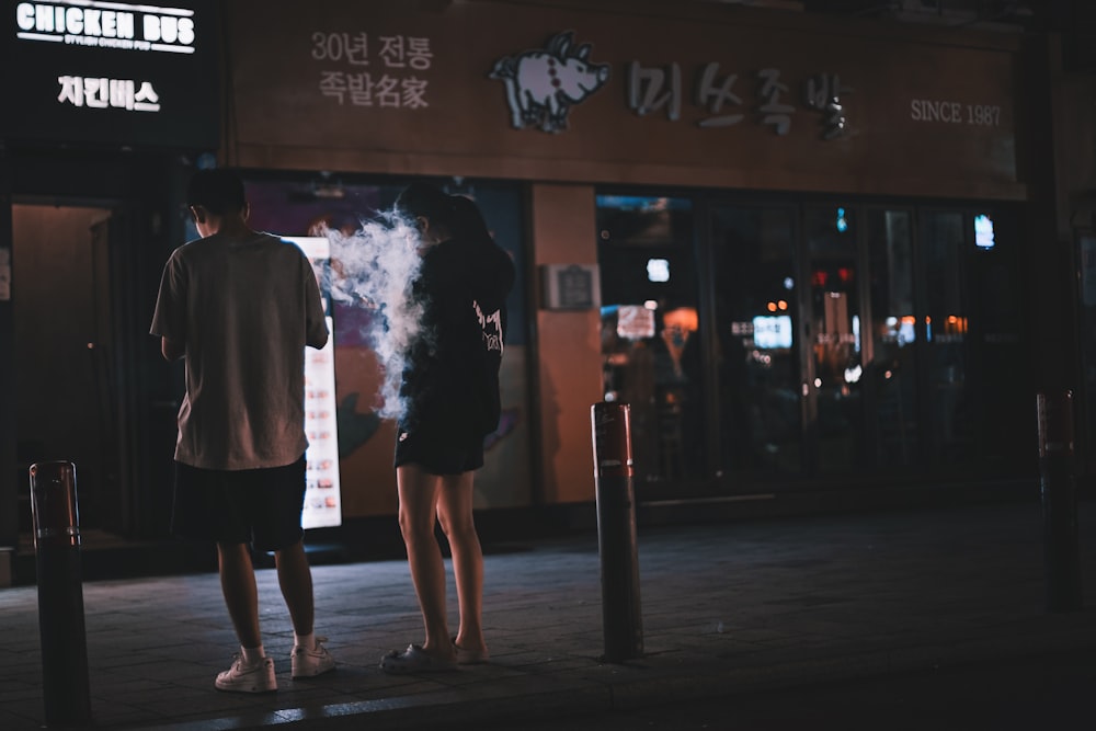a man and a woman standing on a sidewalk at night