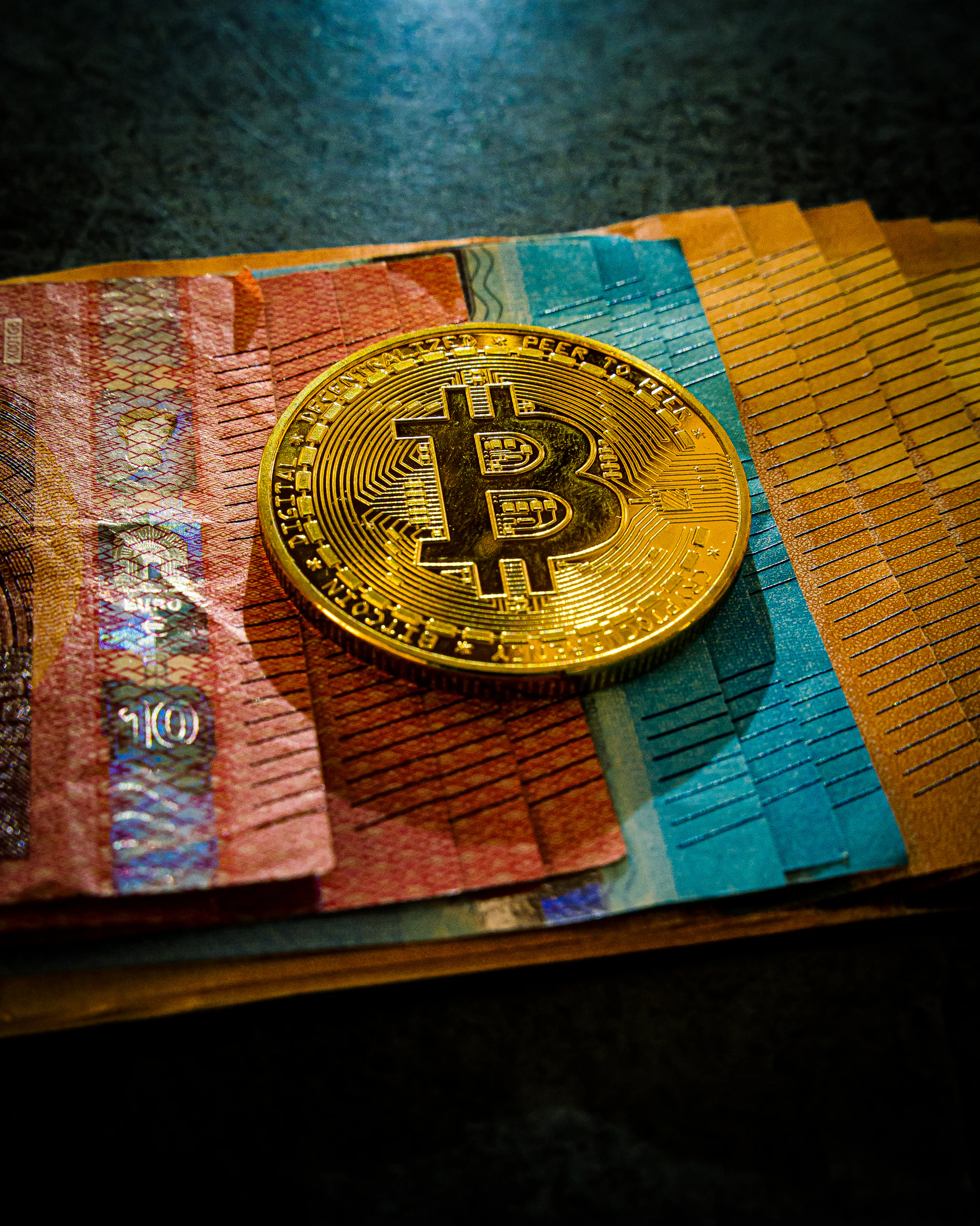 a bitcoin sitting on top of a colorful piece of paper
