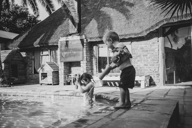 Children playing happily in the villa’s water play zone with palm trees and lounge chairs nearby.