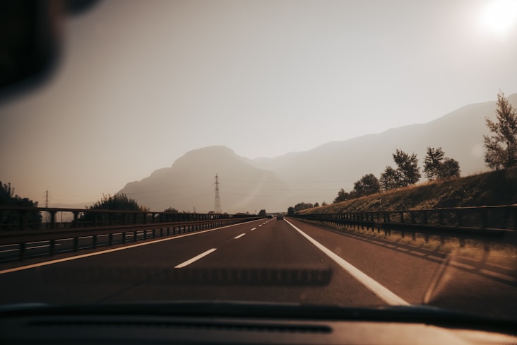 a car driving down a road with mountains in the background