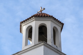 The church bell tower silhouetted against a clear blue sky on a bright day.