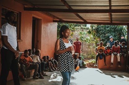 A group of teenage mothers attentively participating in a life skills training session under a shaded outdoor area.