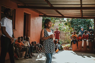 A vibrant group of women and children engaged in a community learning session outdoors.