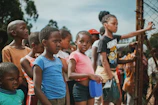 A group of smiling children in Ethiopia receiving fresh food supplies under a bright sky.