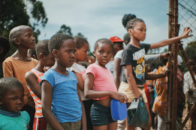 A group of smiling children in Ethiopia receiving fresh food supplies under a bright sky.