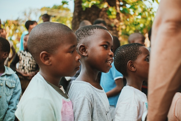 A group of children engaged in a supportive mentoring session outdoors.