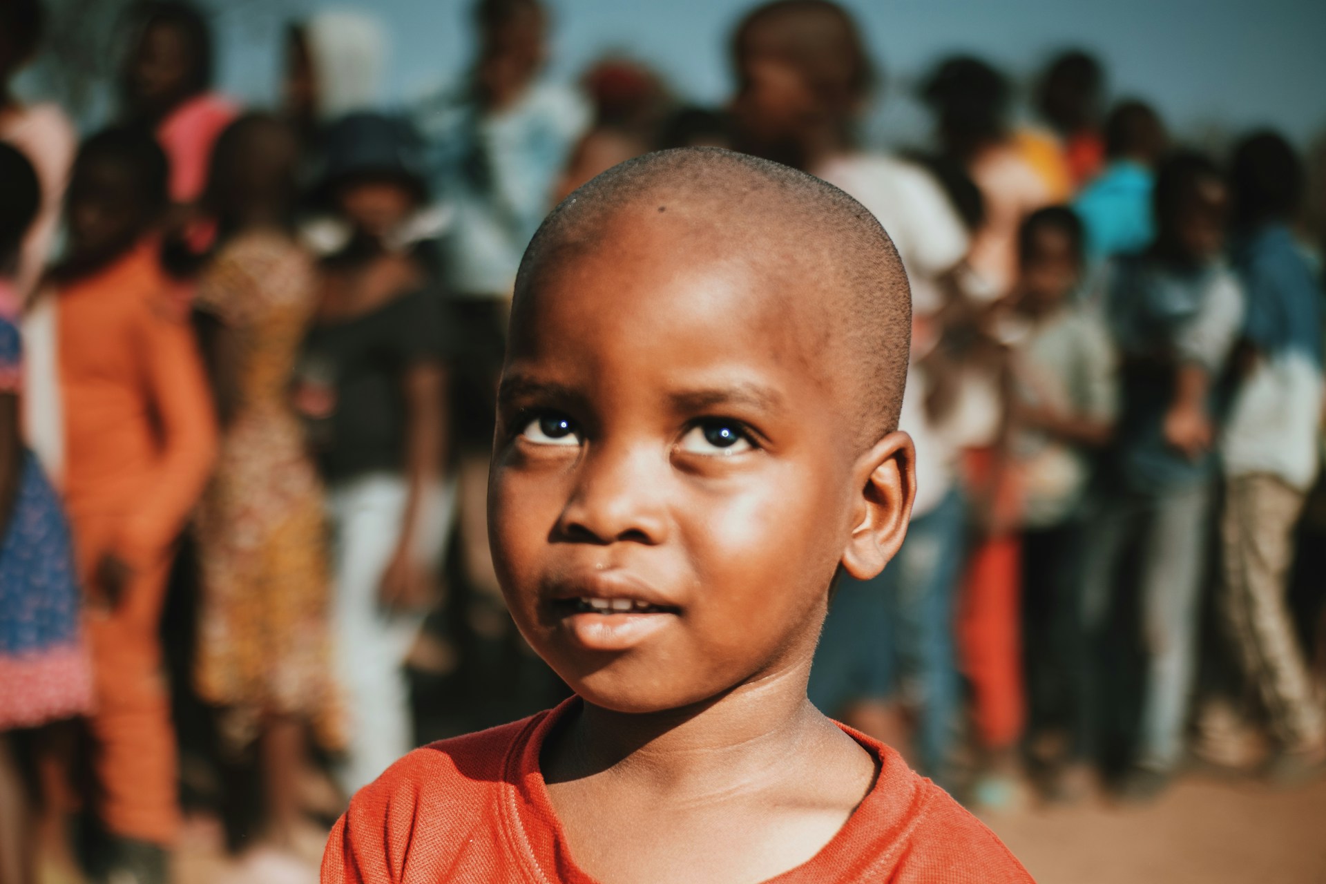 a young boy standing in front of a crowd of people