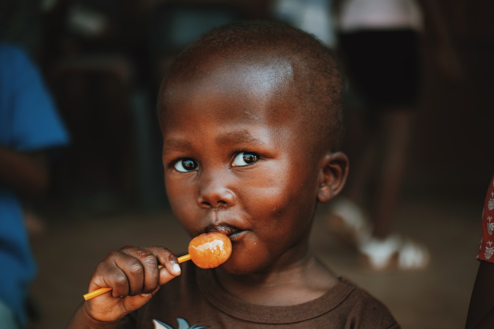 a young boy holding an orange in his mouth