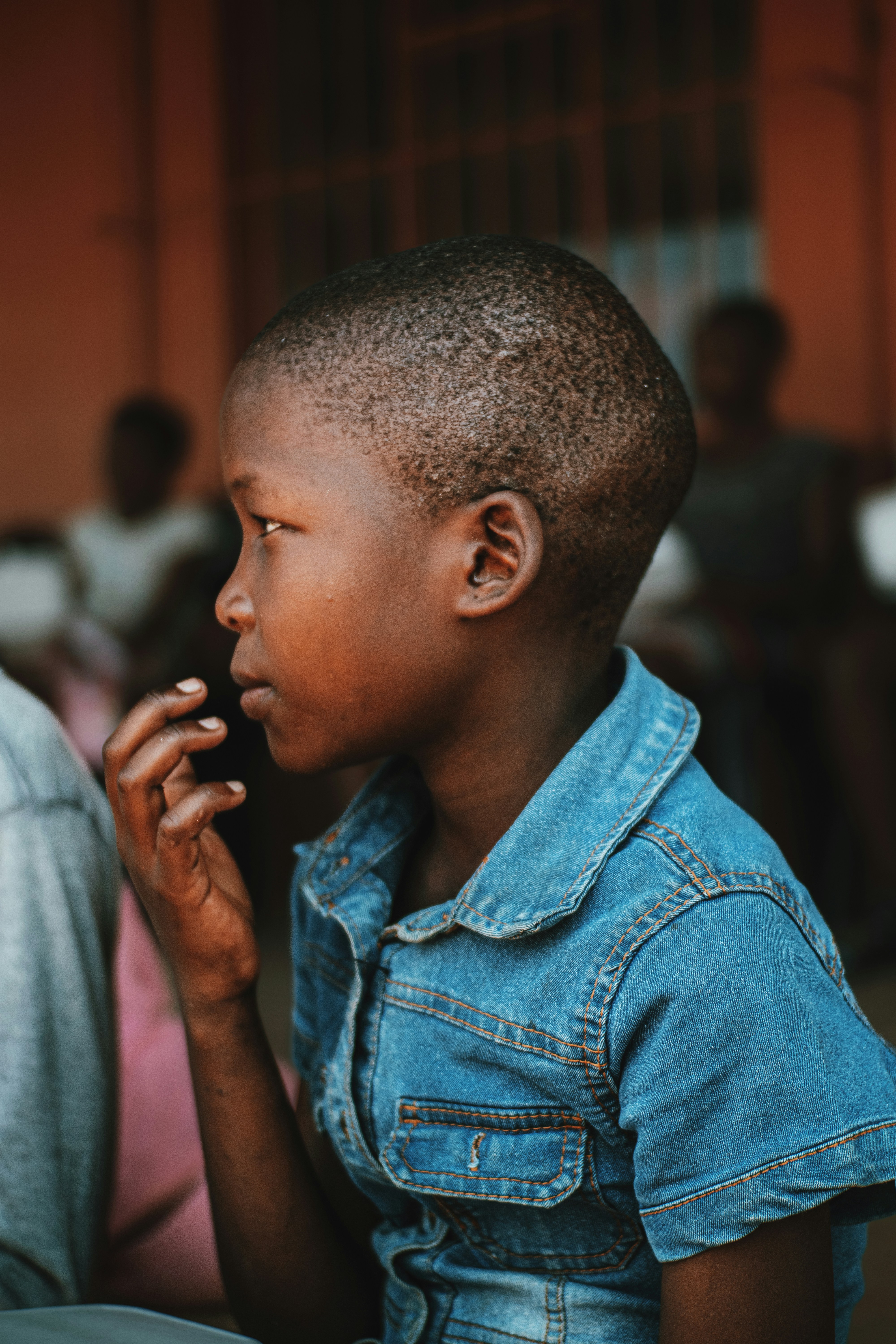 a young boy in a denim shirt talking on a cell phone