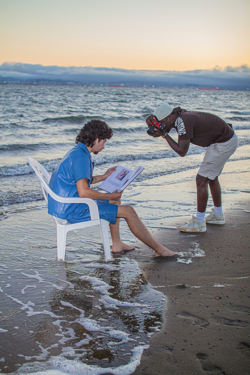 a man sitting in a chair on the beach reading a magazine