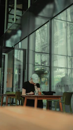 a person sitting at a table in front of a window