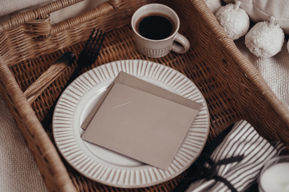 a wicker tray with a plate, napkins, and a cup of coffee