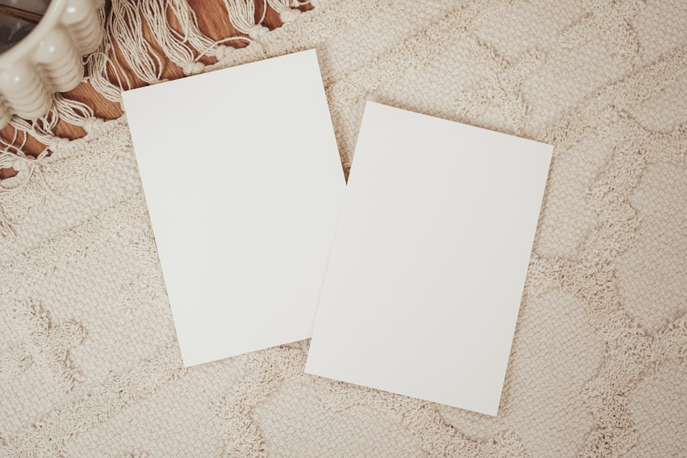 two blank cards sitting on top of a bed