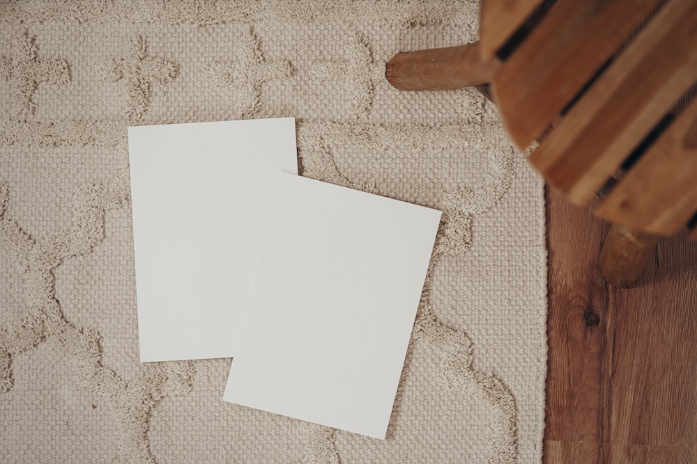 two white sheets of paper sitting on top of a rug