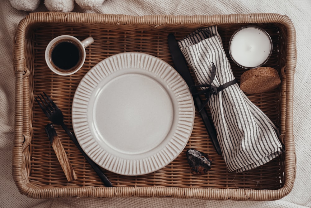 a wicker tray topped with a plate and a cup of coffee