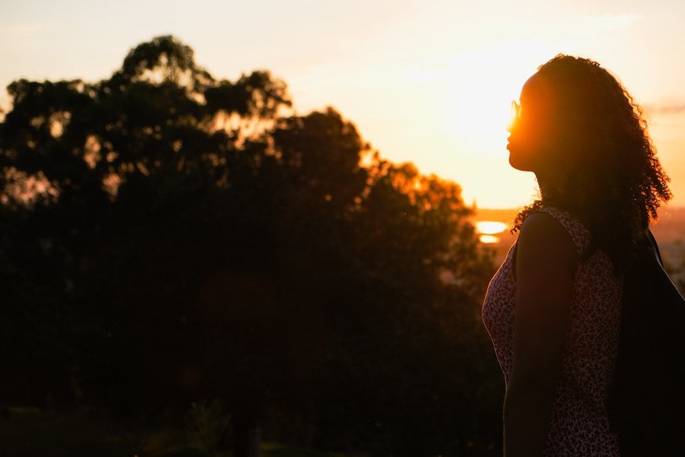 a woman standing in front of a sunset