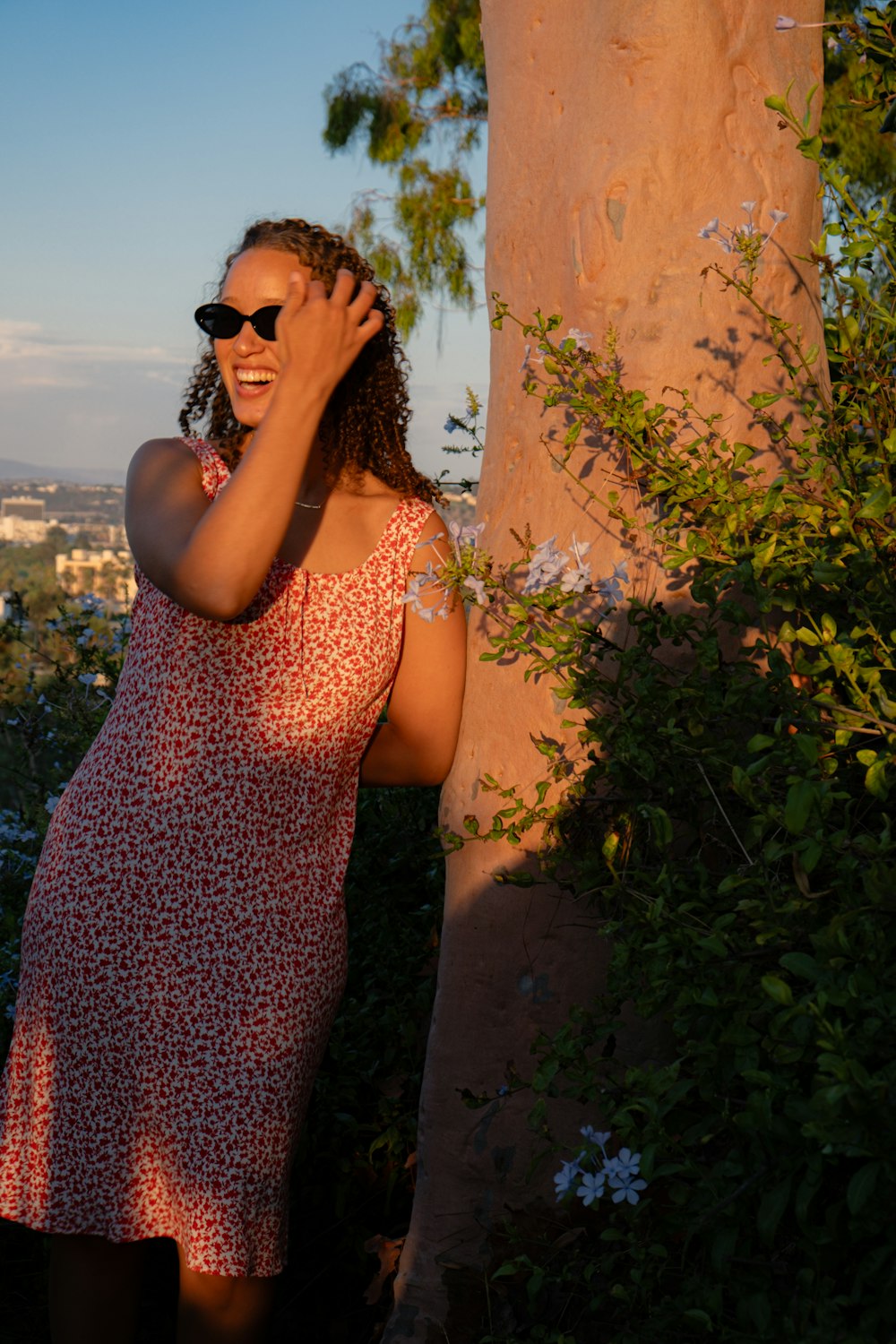 a woman in a red dress standing next to a tree