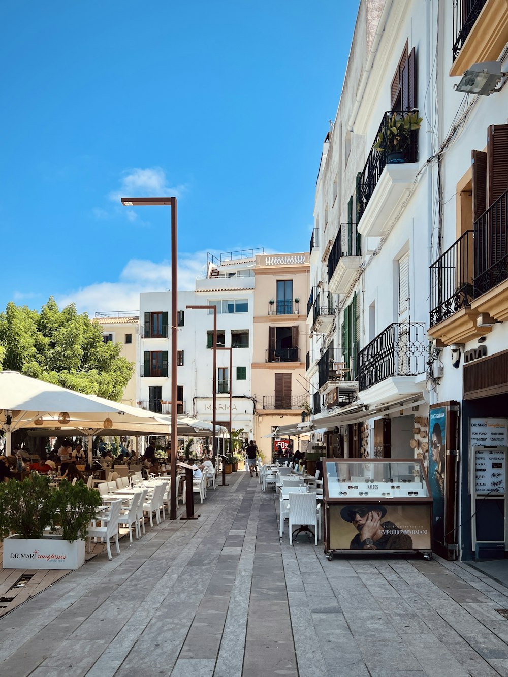 a city street with tables and umbrellas on both sides of the street